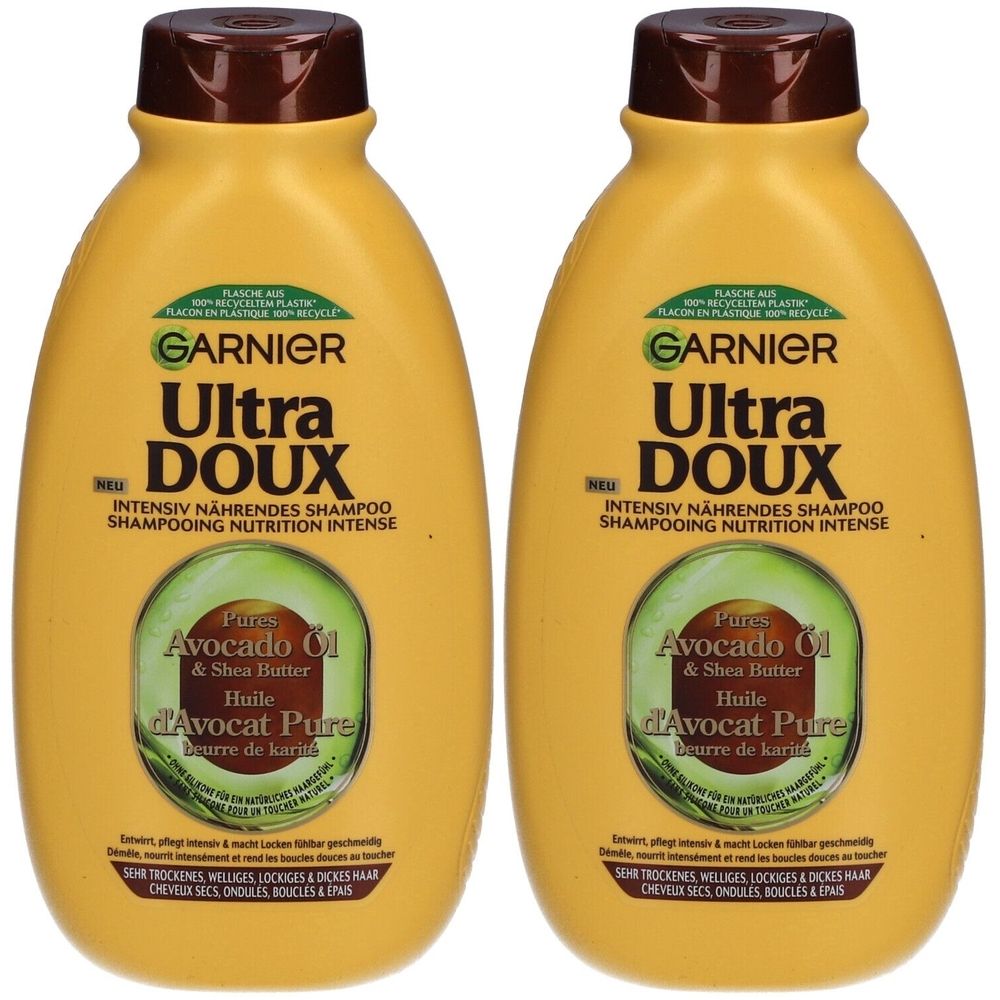 Deux flacons jaunes de shampooing Garnier Ultra Doux. Huile d'avocat et beurre de karité. Bouchon marron, étiquettes vertes.