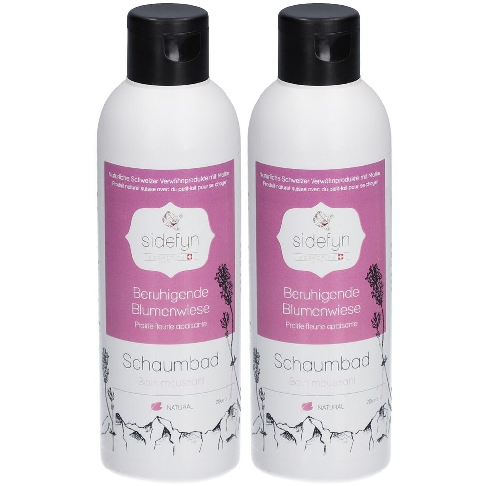 Twee witte flessen met zwarte dop. Etiketten met productnaam en logo. Tekst: Beruhigende Blumenwiese, Schaumbad.