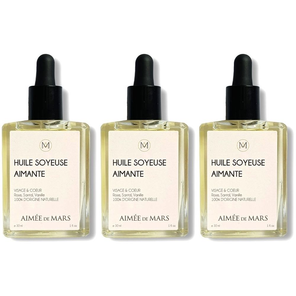 Drie vierkante glazen flessen met zwarte druppelaar. Op het etiket staat "HUILE SOYEUSE AIMANTE" en "AIMÉE DE MARS".