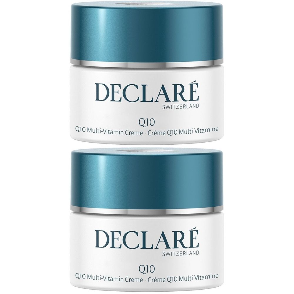 Twee crèmepotten met blauwe deksels. Opschrift: DECLARÉ SWITZERLAND, Q10 Multi-Vitamin Crème. Witte pot met blauw deksel.