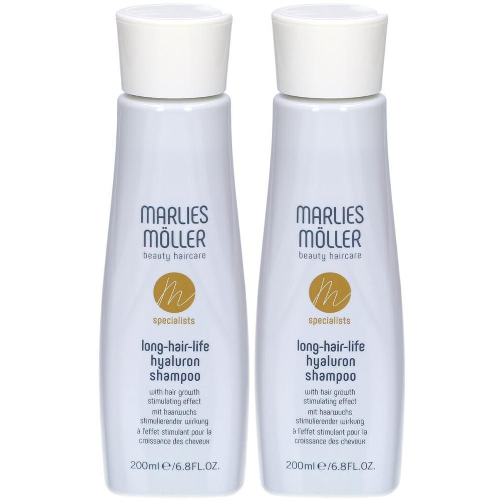 Twee flessen Marlies Möller shampoo. Wit, cilindrisch, met witte dop. Goudkleurig logo en tekst.