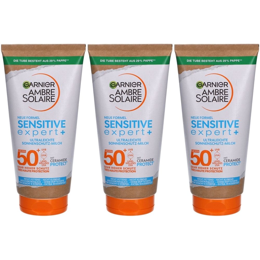 Trois tubes de Garnier Ambre Solaire Sensitive Expert+ SPF 50+. Tube blanc avec bouchon marron et texte visible.