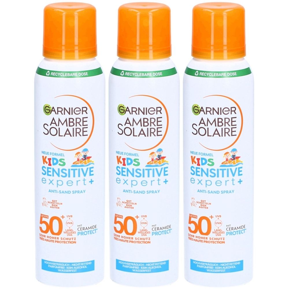 Drie sprays van Garnier Ambre Solaire Kids Sensitive Expert+ SPF50+. Witte flessen met oranje doppen. Tekst: Anti-Sand Spray.