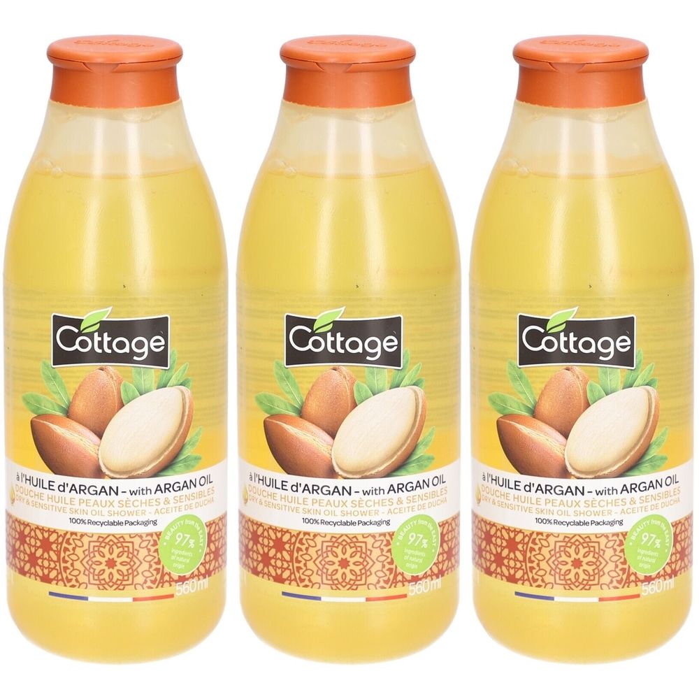 Drie flessen douche-olie met arganolie. Gele vloeistof in transparante flessen met oranje doppen. Opschrift: Cottage, arganolie.