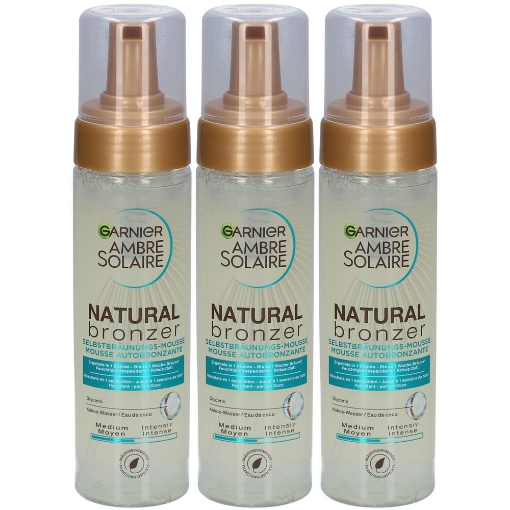 Drie flessen Garnier Ambre Solaire Natural Bronzer zelfbruiningsmousse. Transparante flessen met gouden pompkop en dop.