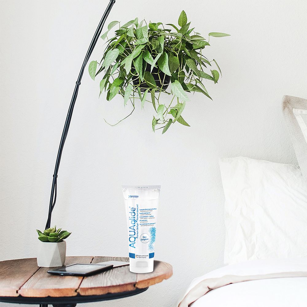 Gel AQUAglide, tube. Sur une table de chevet. Propriétés lubrifiantes longue durée, compatible avec les préservatifs, soluble dans l'eau, sans graisse, pH optimisé.