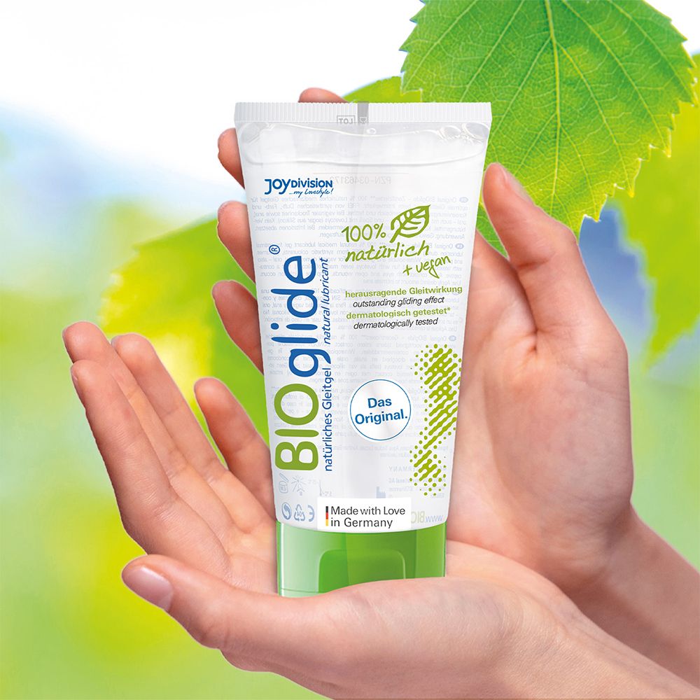 Mains tenant un tube BIOglide, gel lubrifiant naturel. 100% naturel + végétalien. Design vert et blanc.