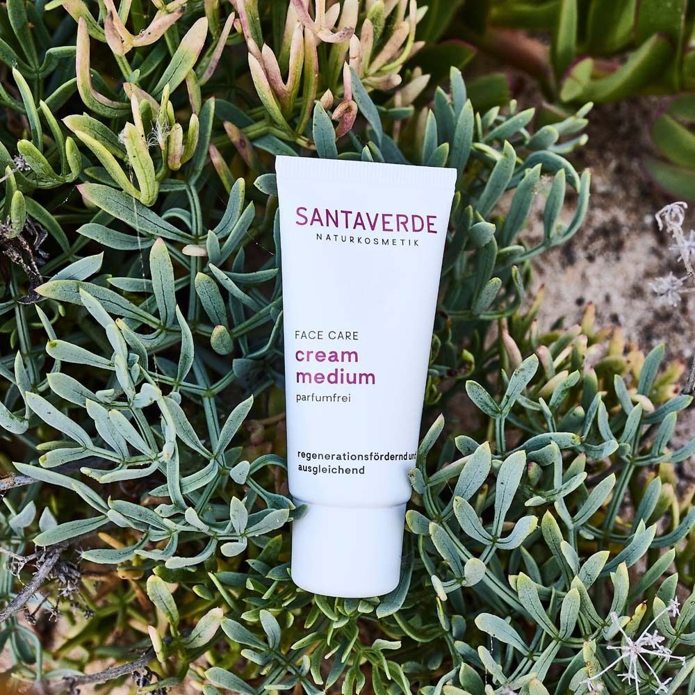 Tube blanche avec logo SANTAVERDE et inscription "FACE CARE cream medium sans parfum" sur plantes.