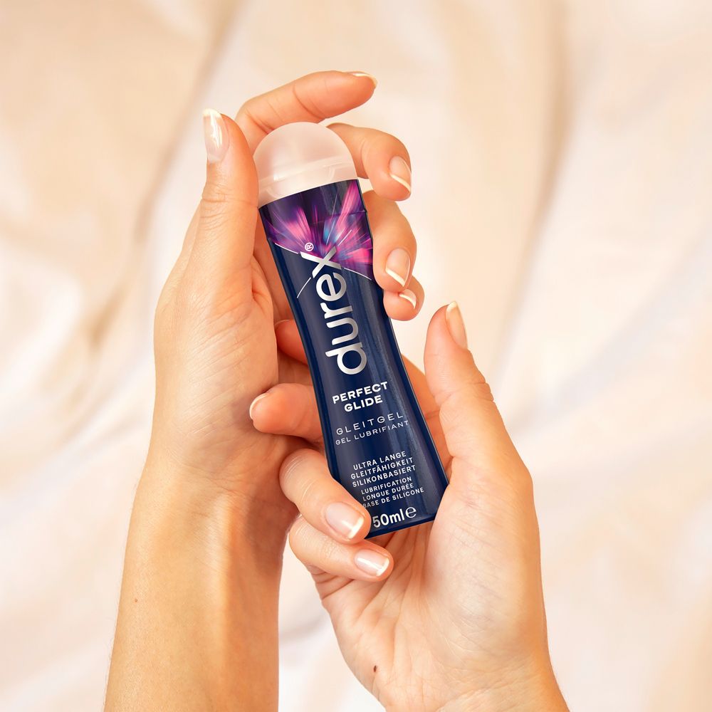 Mains tenant un flacon de gel lubrifiant Durex Perfect Glide.