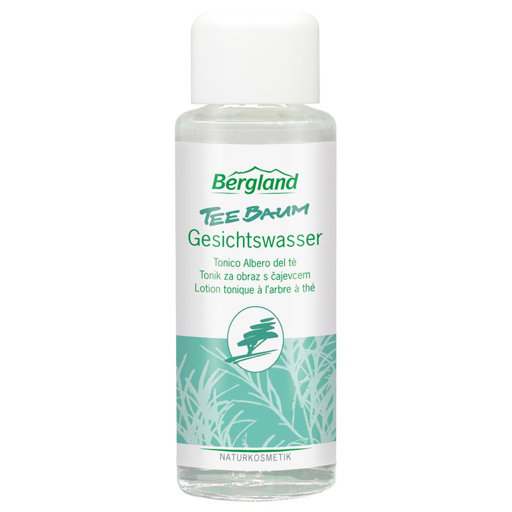 Flacon transparent avec bouchon blanc. Inscription: Bergland Teebaum Gesichtswasser. Étiquette verte et blanche avec logo arbre.