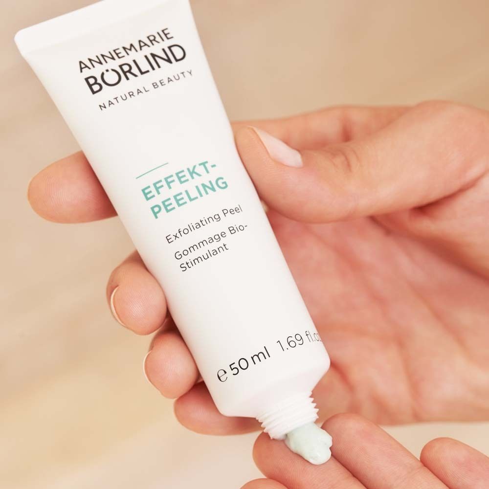 Hand die EFFEKT-PEELING uit een witte tube drukt. Groene peelingtextuur op vinger.