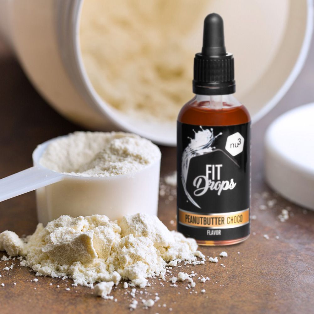 Fles met bruine vloeistof en druppelaar naast een maatlepel en eiwitpoeder. Opschrift: FIT Drops Peanutbutter Choco Flavor.