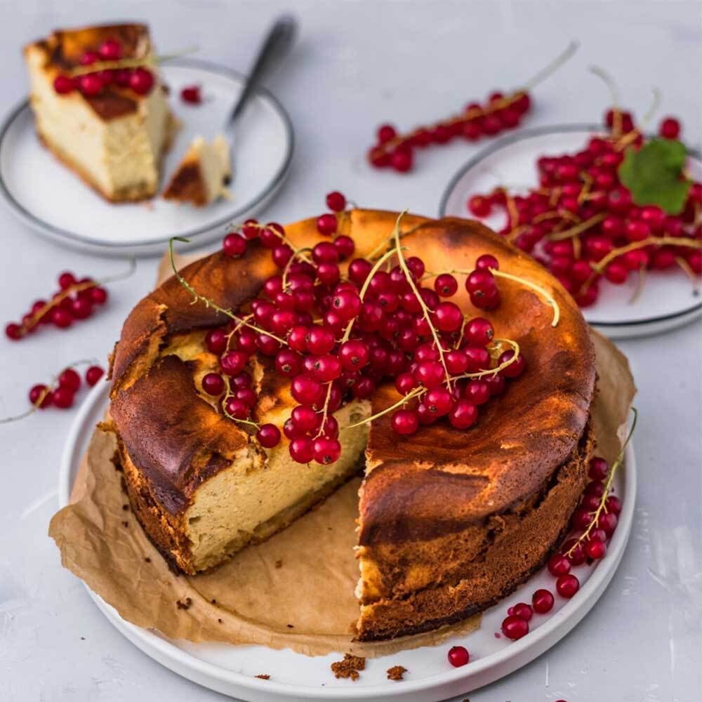 Cheesecake met rode bessen. Op een bord, met andere borden met bessen.