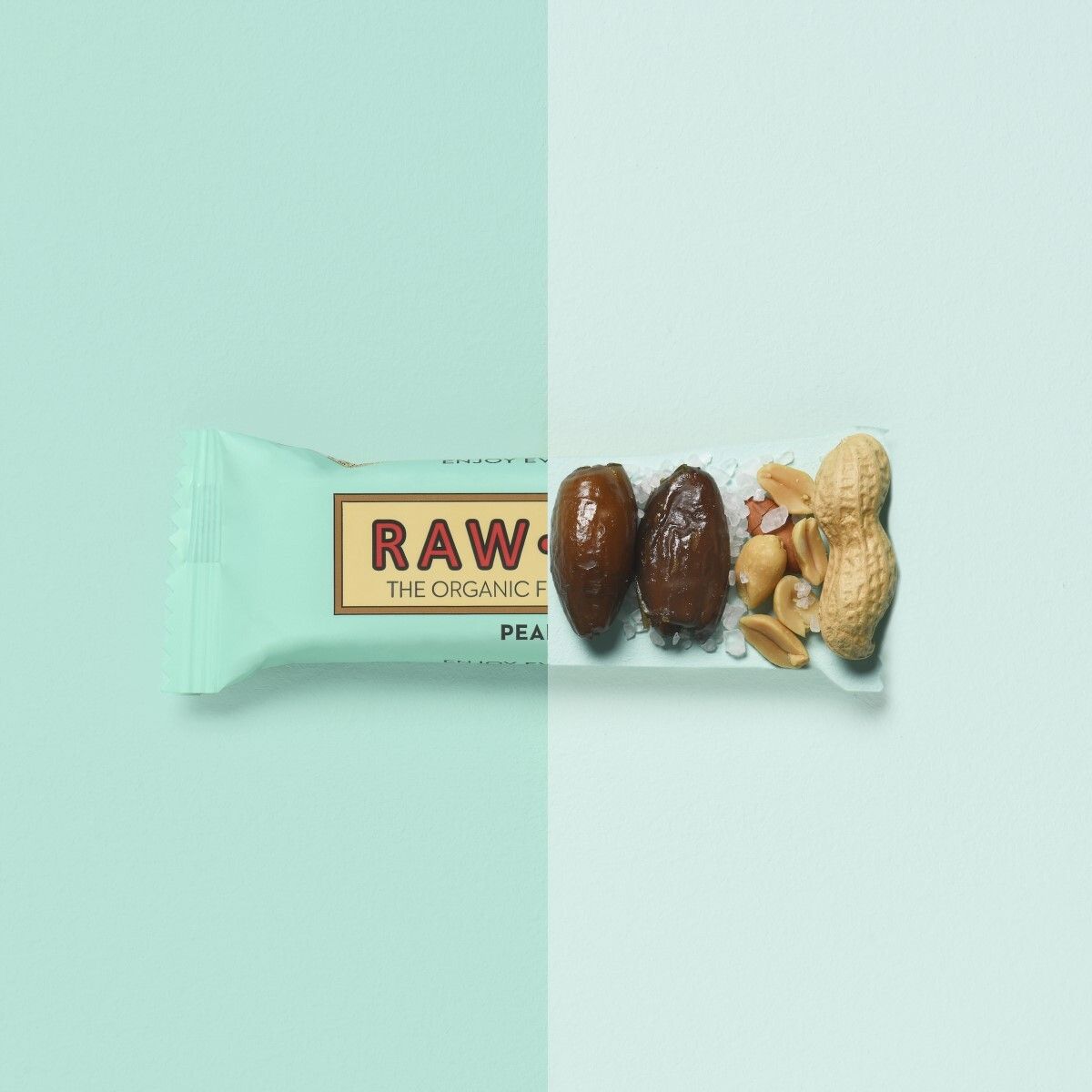 Verpakte reep en ingrediënten. Opschrift: RAW BITE, THE ORGANIC FRUIT & NUT BITE, PEANUT. Lichtblauwe verpakking.