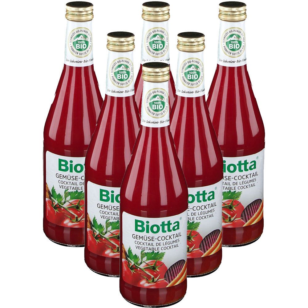 Zeven flessen Biotta Gemüse-Cocktail. Rode vloeistof in glazen flessen met gouden doppen. Etiketten met logo en productnaam.