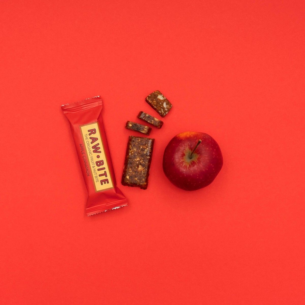 Rood oppervlak met reep, reepstukjes en appel. Opschrift RAWBITE zichtbaar.
