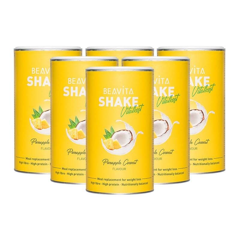 Six boîtes de BEAVITA Vitalkost Diät-Shake, saveur Coco-Ananas, entourées d'ananas et de noix de coco.