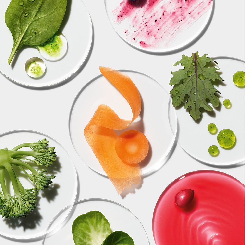Verschillende ingrediënten op transparante platen: wortelen, groenten, bessen en groene bladeren.
