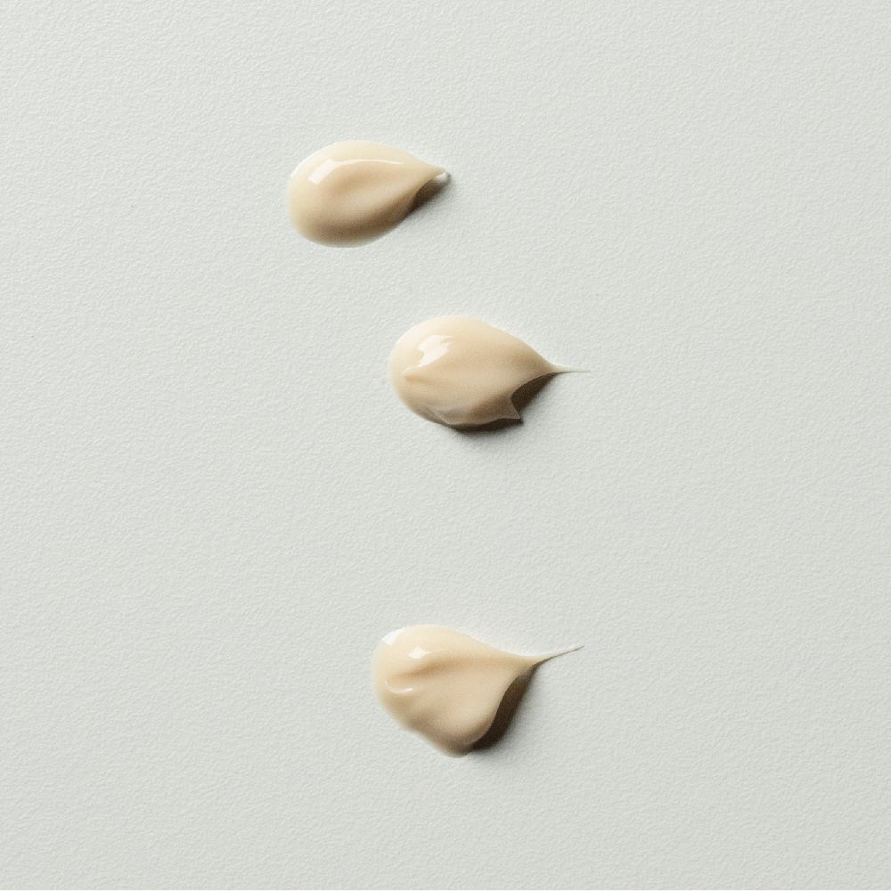 Drie crèmekleurige druppels op witte achtergrond. Consistentie: romig, glad.