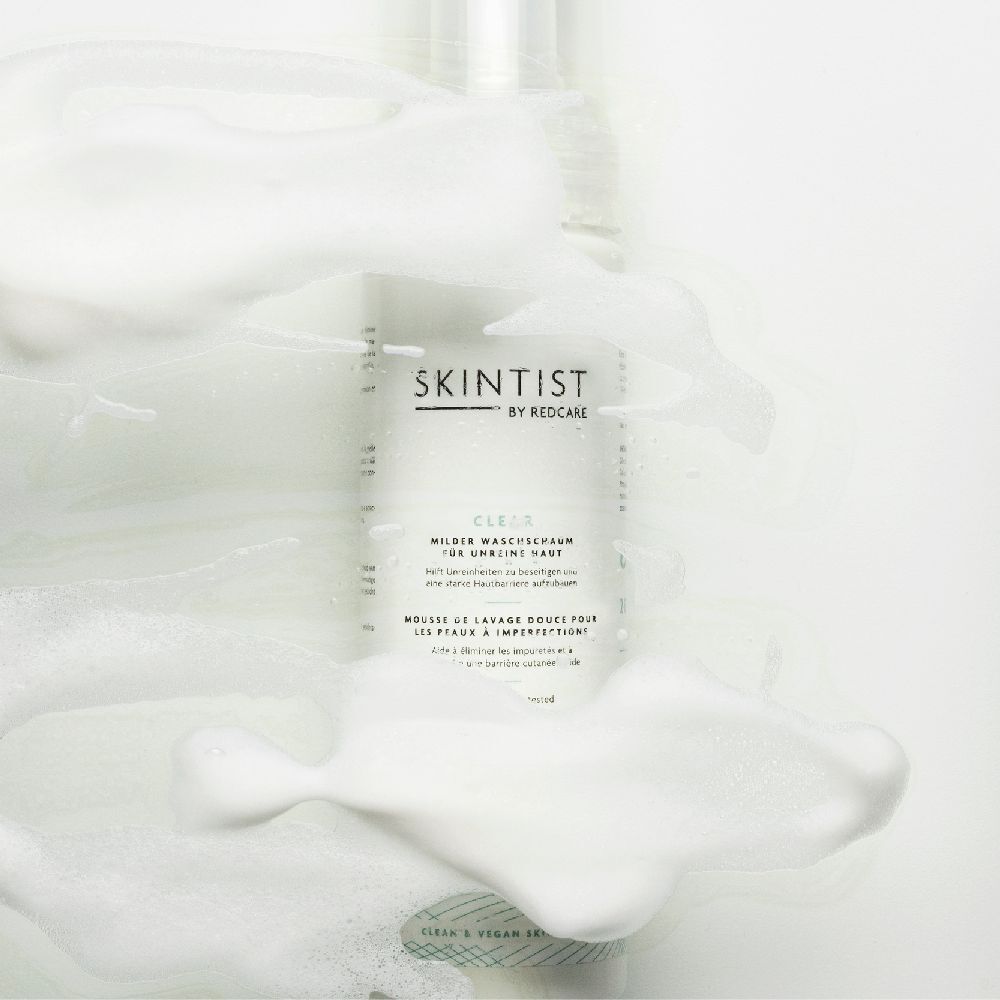 SKINTIST CLEAR wasschuimfles omringd door wit schuim. Productlabel zichtbaar.