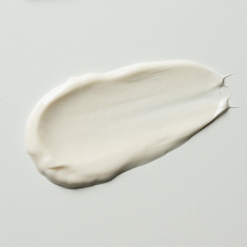 Une noisette de crème sur fond blanc. La crème est blanche et a une texture lisse.