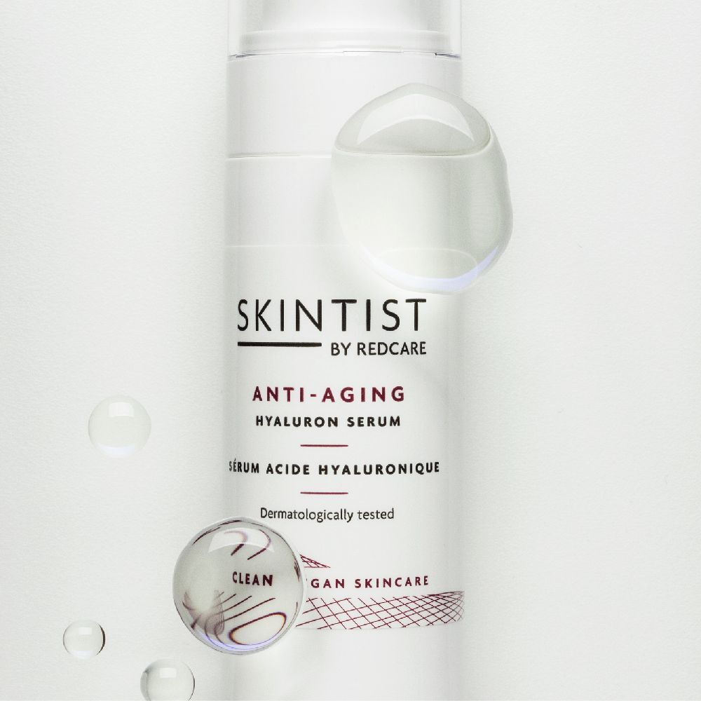 Witte fles met pomp. Opschrift: SKINTIST ANTI-AGING Hyaluron Serum. Dermatologisch getest. Transparante bollen.