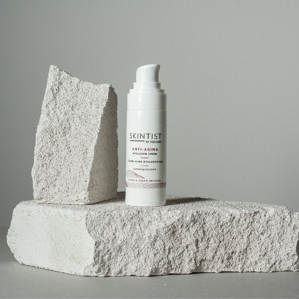 Witte fles met pomp op steen. Opschrift: SKINTIST ANTI-AGING Hyaluron Serum. Dermatologisch getest.