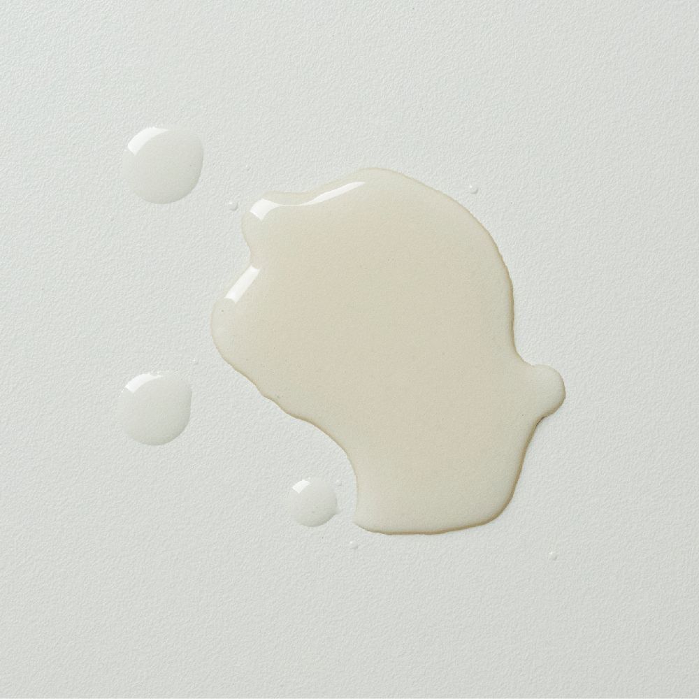 Close-up van drie druppels heldere vloeistof op een witte ondergrond.