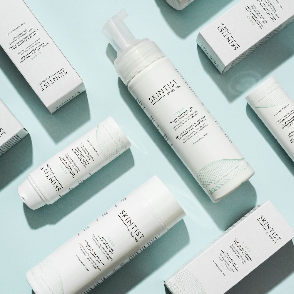 Verschillende SKINTIST-producten, waaronder toners en crèmes, op een blauwe achtergrond. Opschrift: SKINTIST.