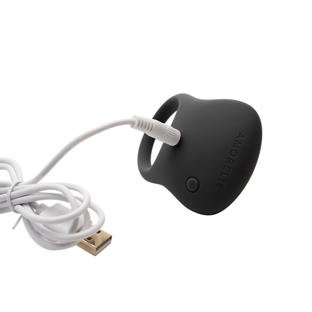 Grijze penisring met USB-kabel. Knoppen zichtbaar. AMORELIE-logo.