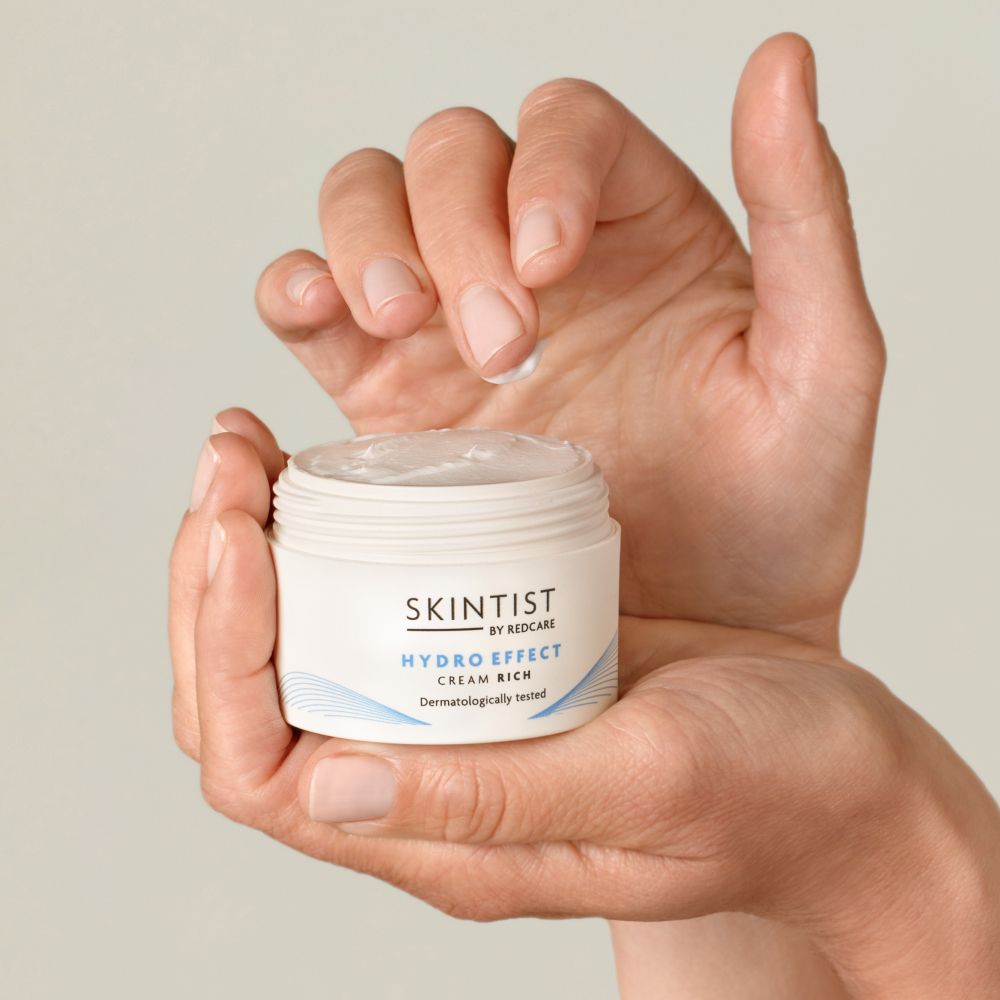 Een hand houdt een witte pot SKINTIST HYDRO EFFECT Cream Rich vast.