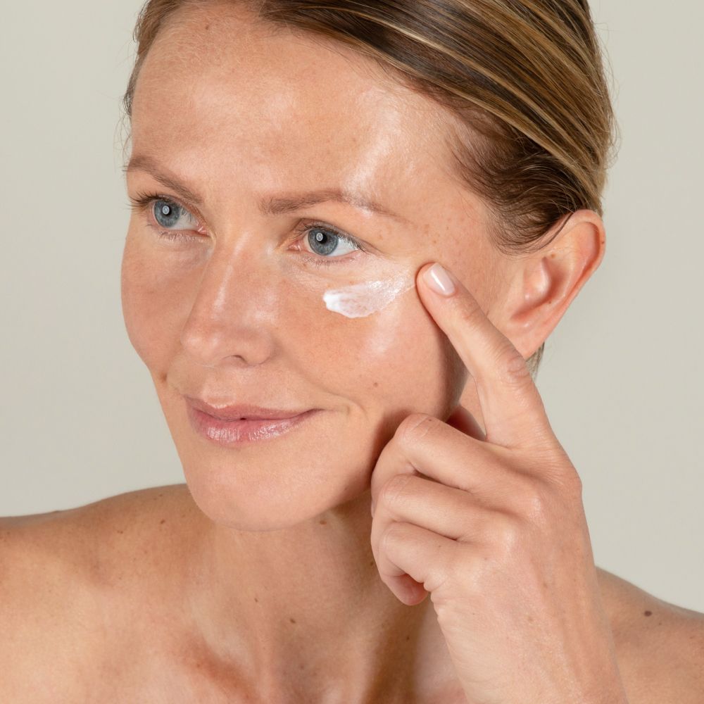 Femme appliquant de la crème pour les yeux. Inscription : SKINTIST HYDRO EFFECT. La crème est appliquée sur la peau.