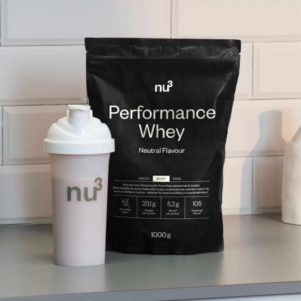Sac noir "nu3 Performance Whey" à côté d'un shaker blanc. Inscriptions : "Neutral Flavor", informations nutritionnelles. Shaker avec logo "nu3".