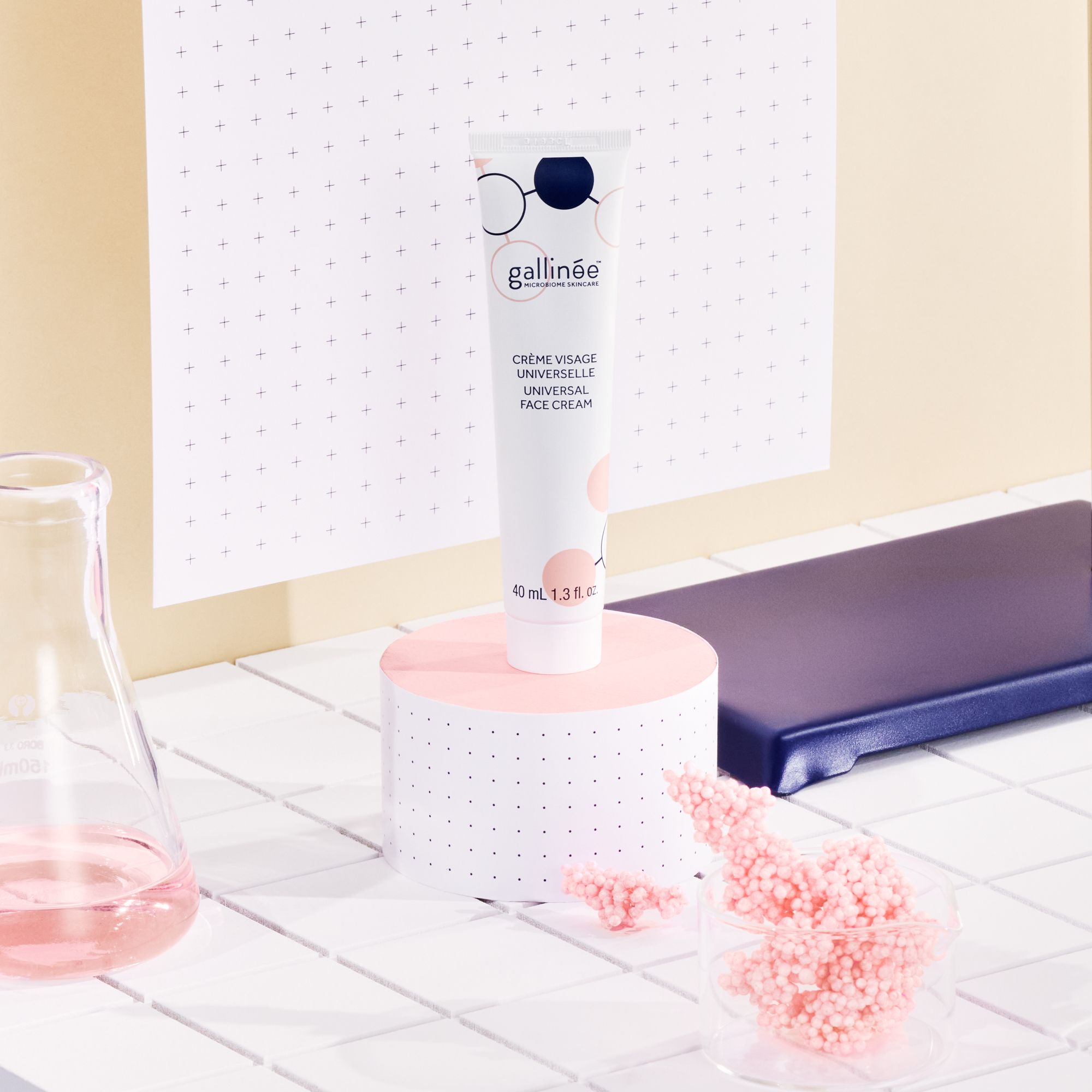 Crèmetube op roze sokkel. Achtergrond: roze en wit. Tekst: Crème Visage Universelle.