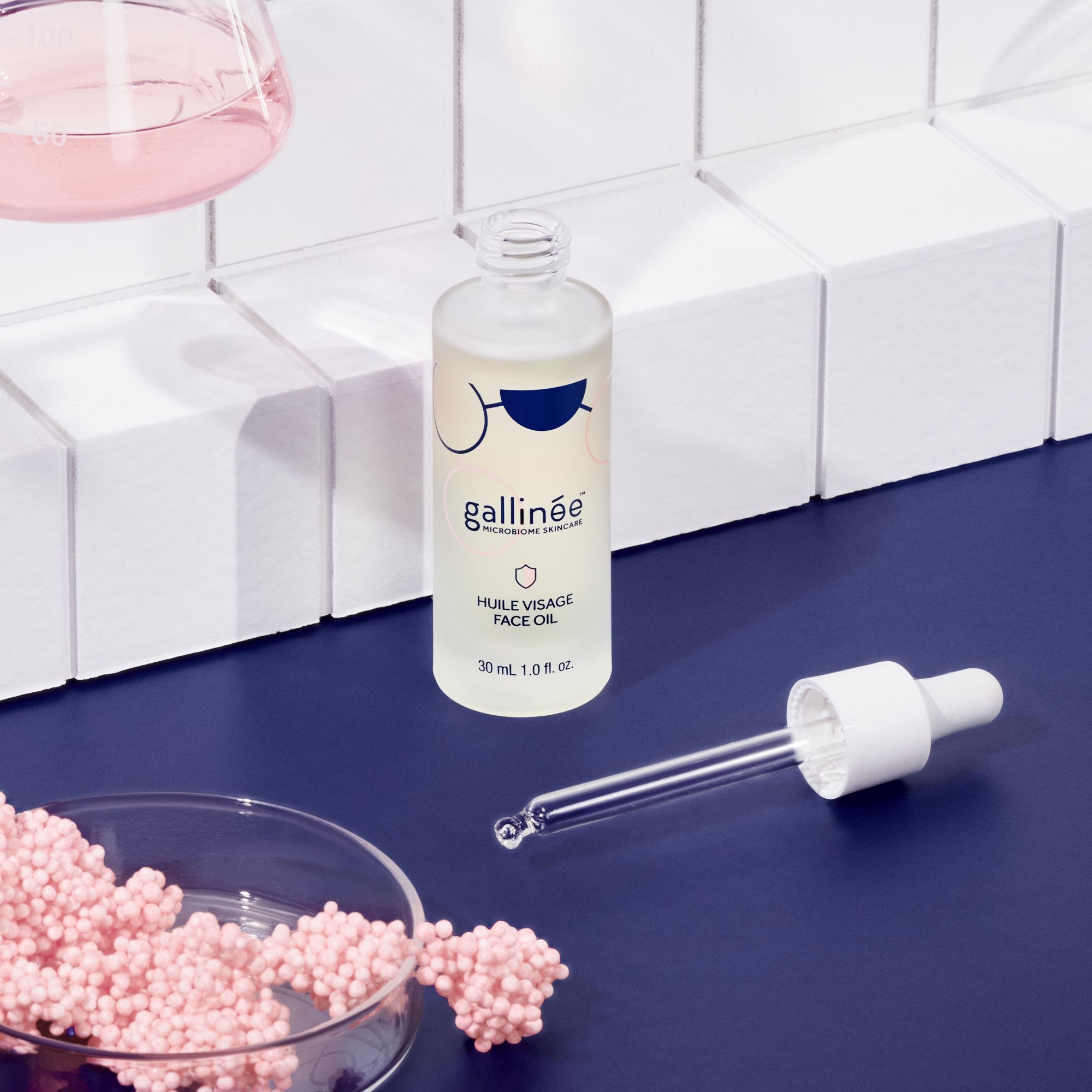 Gezichtsolie fles met pipet en roze bolletjes. Opschrift: Huile Visage Face Oil. 30 ml.