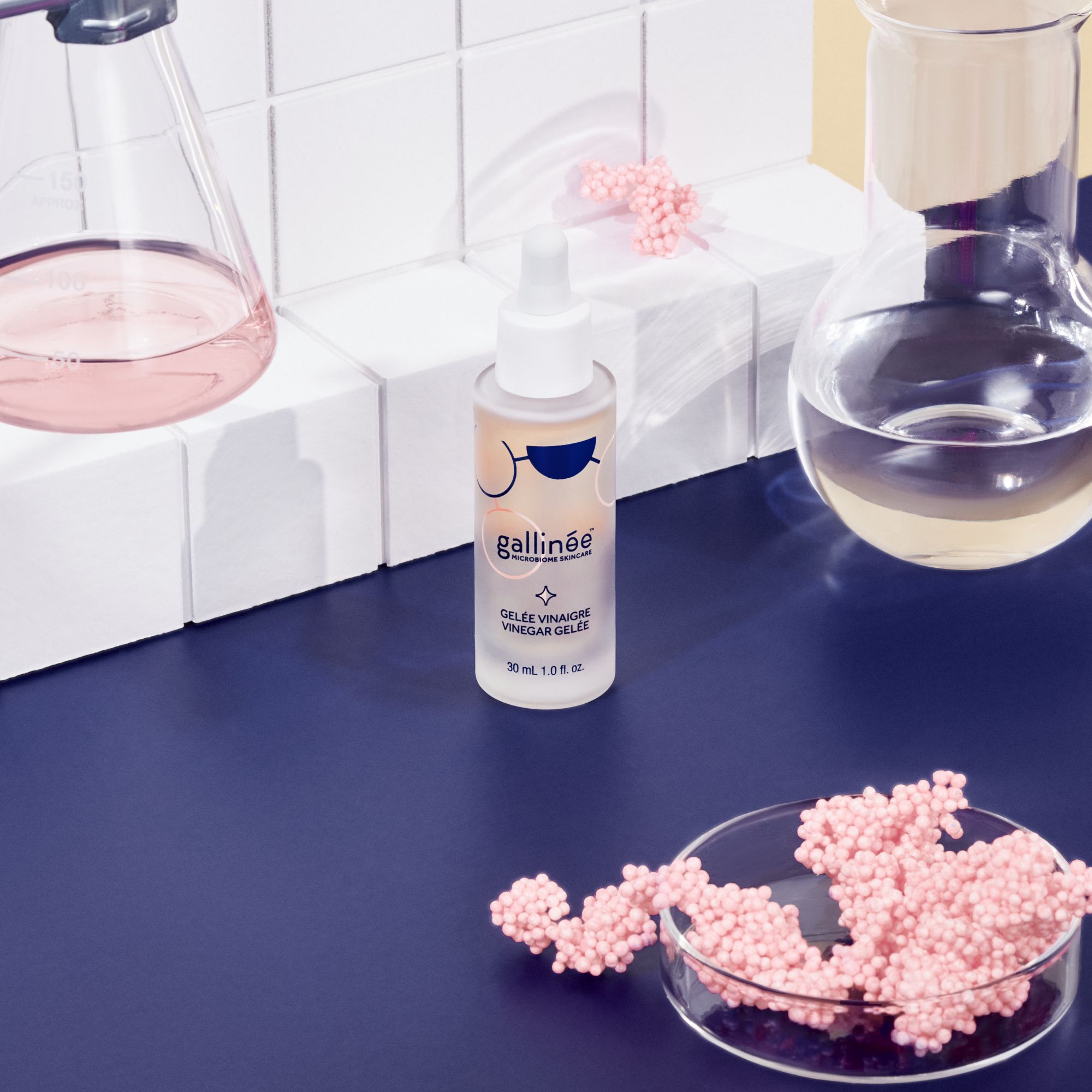 Flacon avec pipette, entouré de matériel de laboratoire et billes roses.