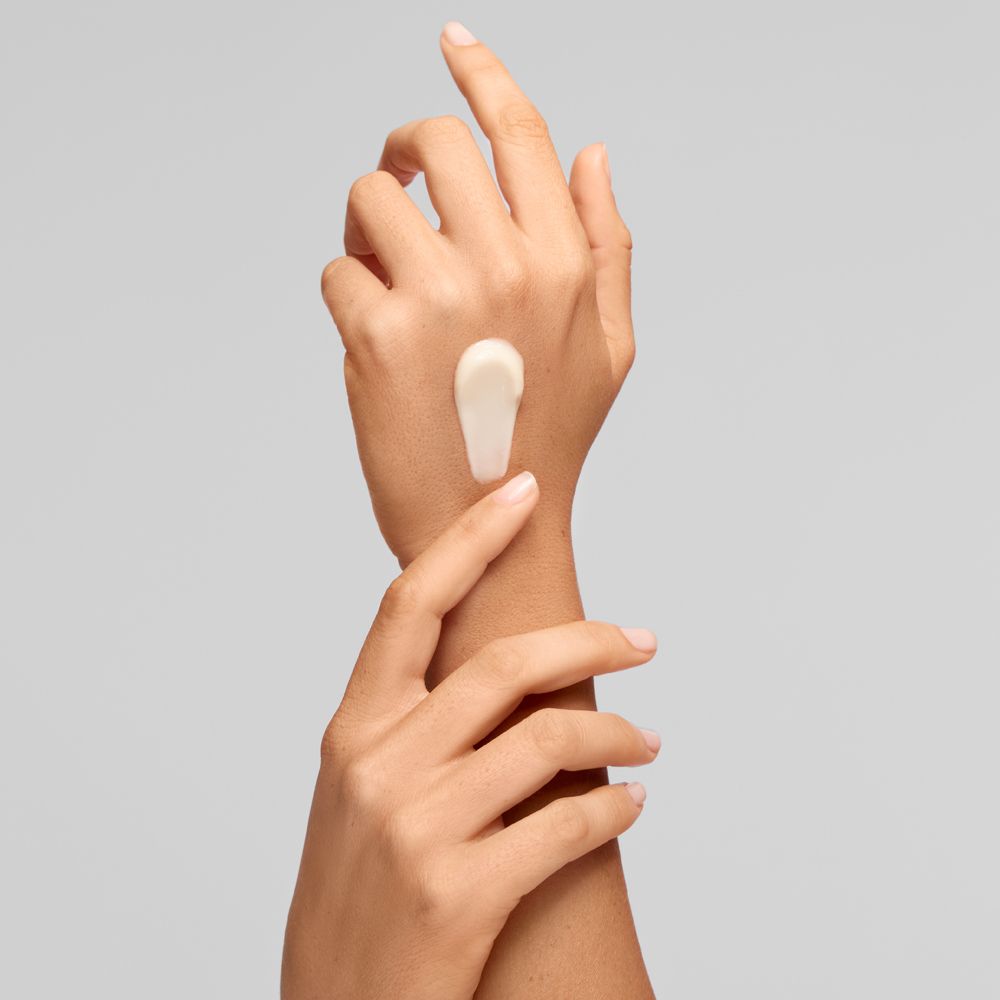 Une crème blanche est appliquée sur le dos de la main.