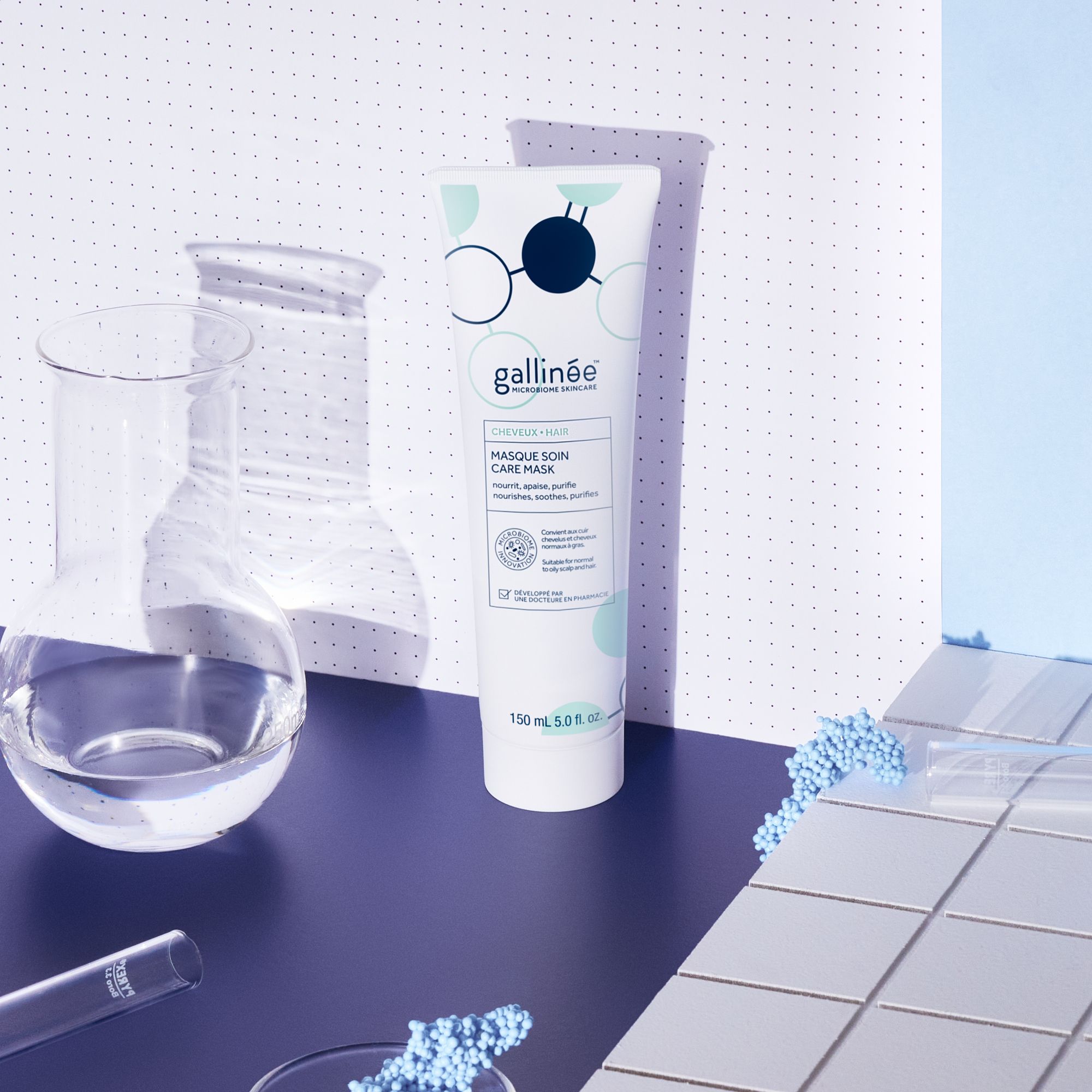 Producttube op blauwe achtergrond met laboratoriummateriaal. Merk: Gallinée. Tekst: Masque Soin Care Mask.