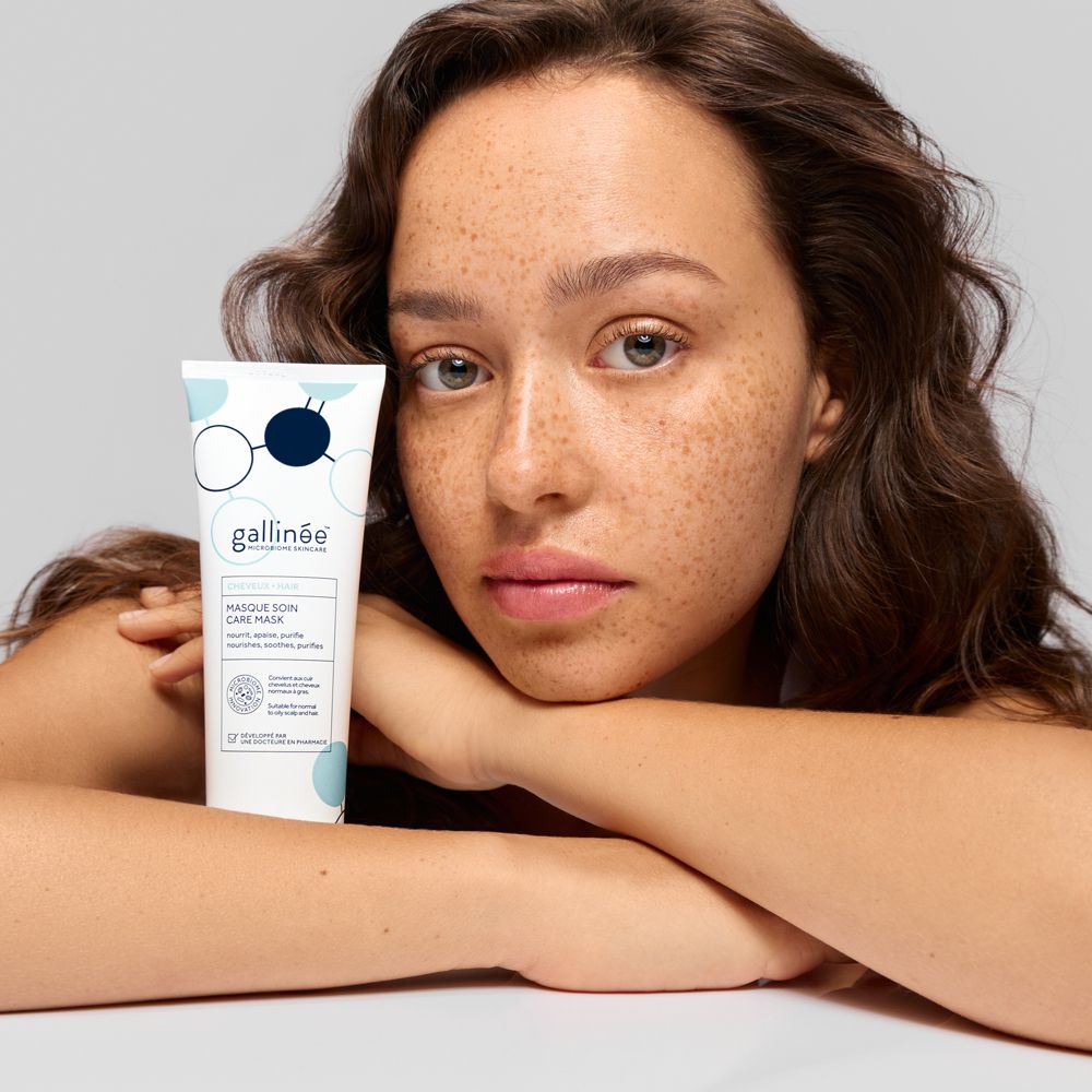Een vrouw houdt een witte tube Gallinée gezichtsmasker vast. De tube heeft een blauw-wit ontwerp.