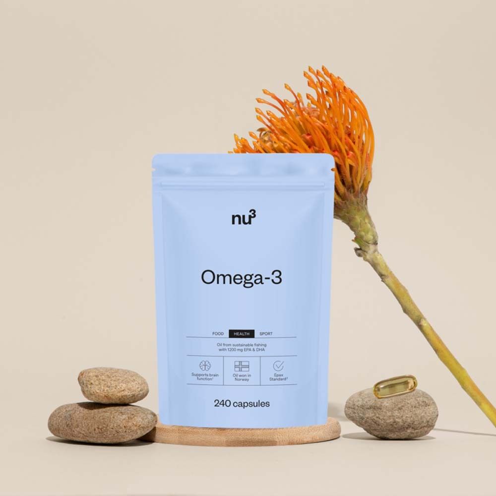 Sachet bleu clair avec "nu3" et "Omega-3" sur socle en bois, avec pierres et fleur. Contient 240 gélules.