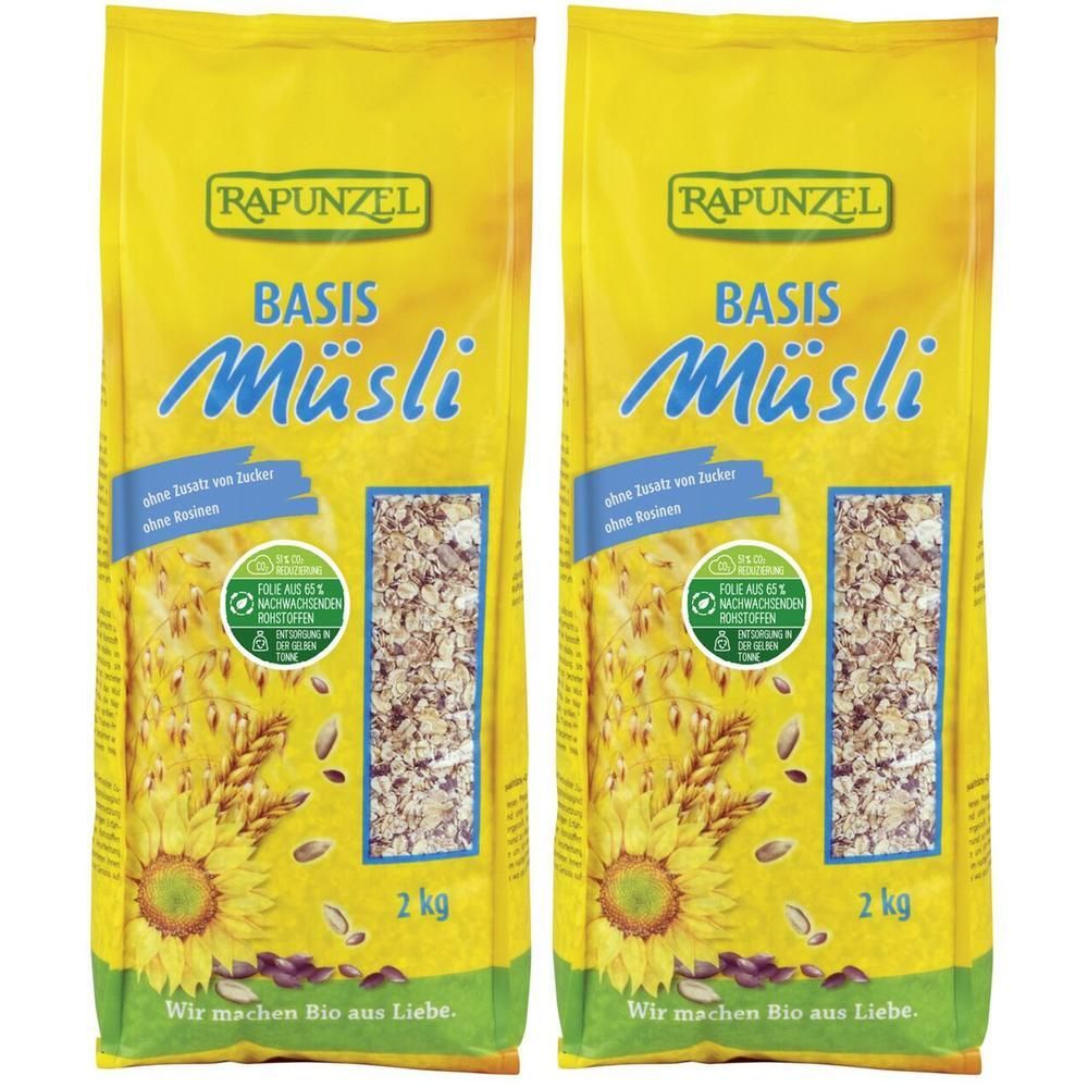 Deux paquets de RAPUNZEL Bio Basis Müsli. Emballage jaune avec nom du produit et informations. 2 kg. Illustration de tournesol.