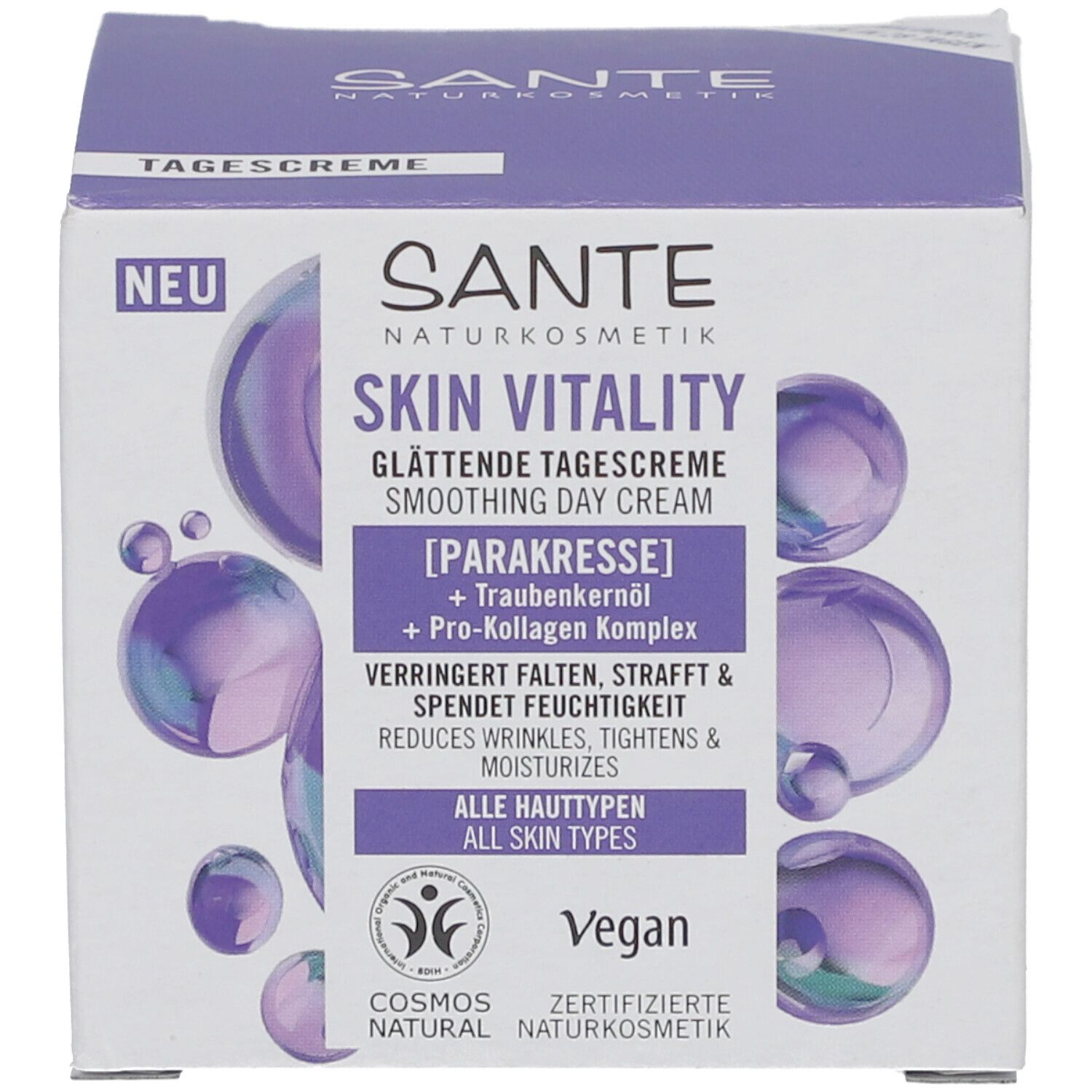 Productverpakking. Opschrift: Sante Skin Vitality Gladmakende dagcrème. Bevat parakerst en druivenpitolie. Vegan. Cosmos Natural-keurmerk.