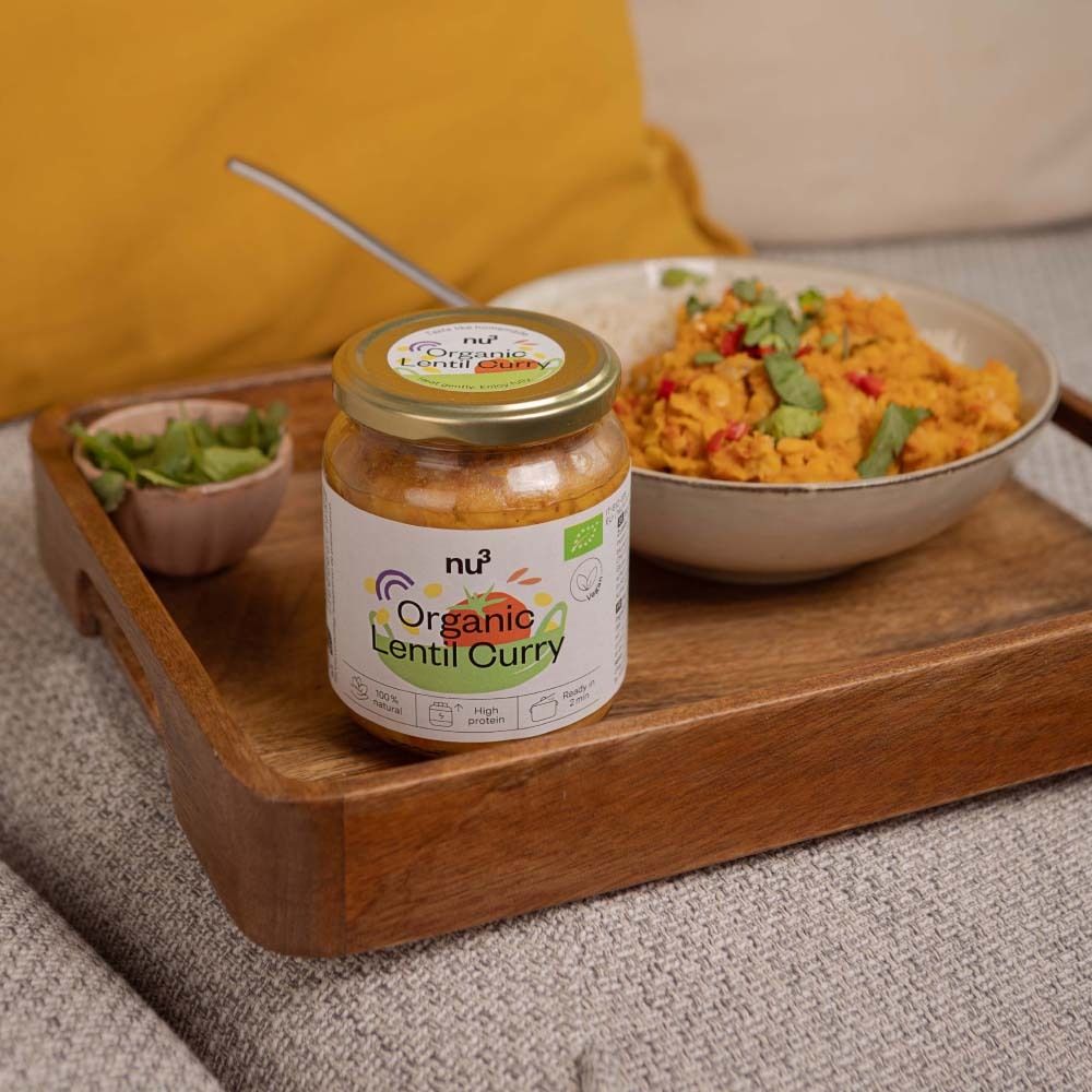 Pot nu3 Organic Linzen Curry op een houten dienblad. Daarnaast een kom met munt en een kom met rijst en curry.