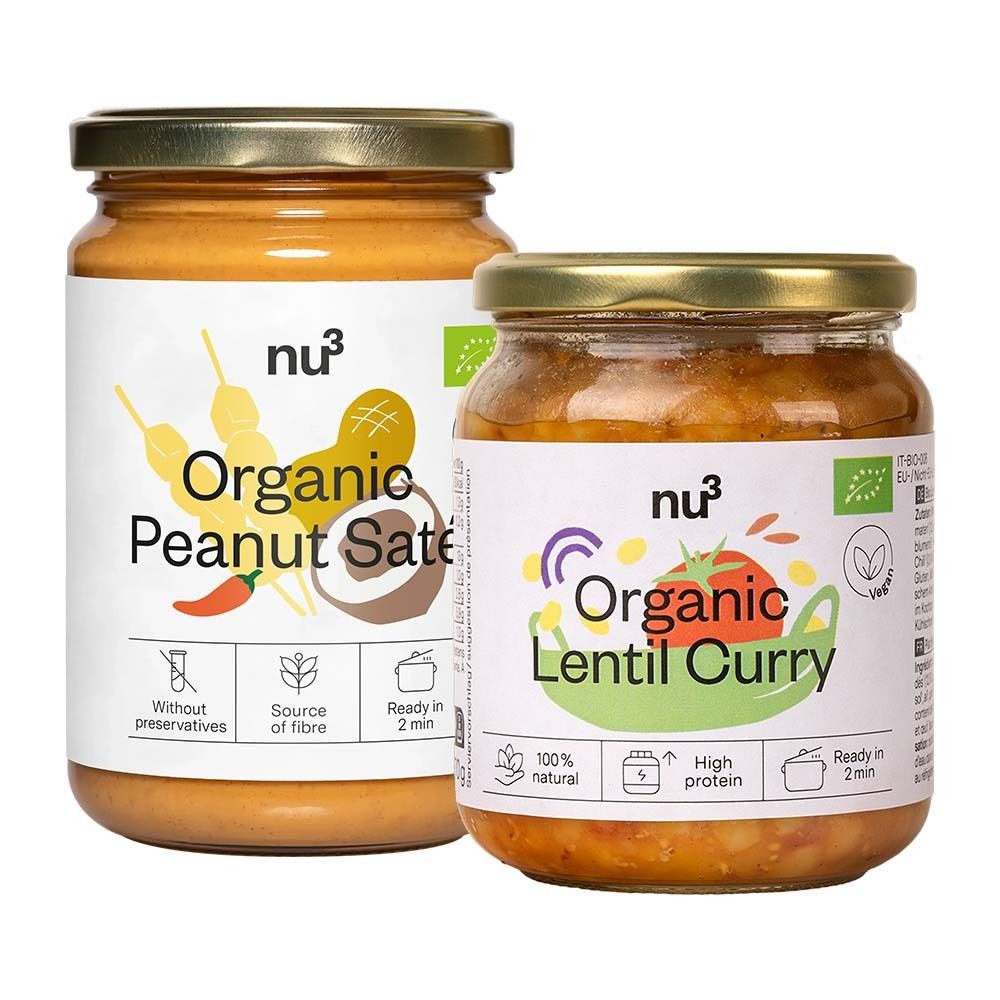 Twee potten met "nu3 Organic Peanut Saté" en "Organic Lentil Curry". Potten met gouden deksels en witte etiketten.