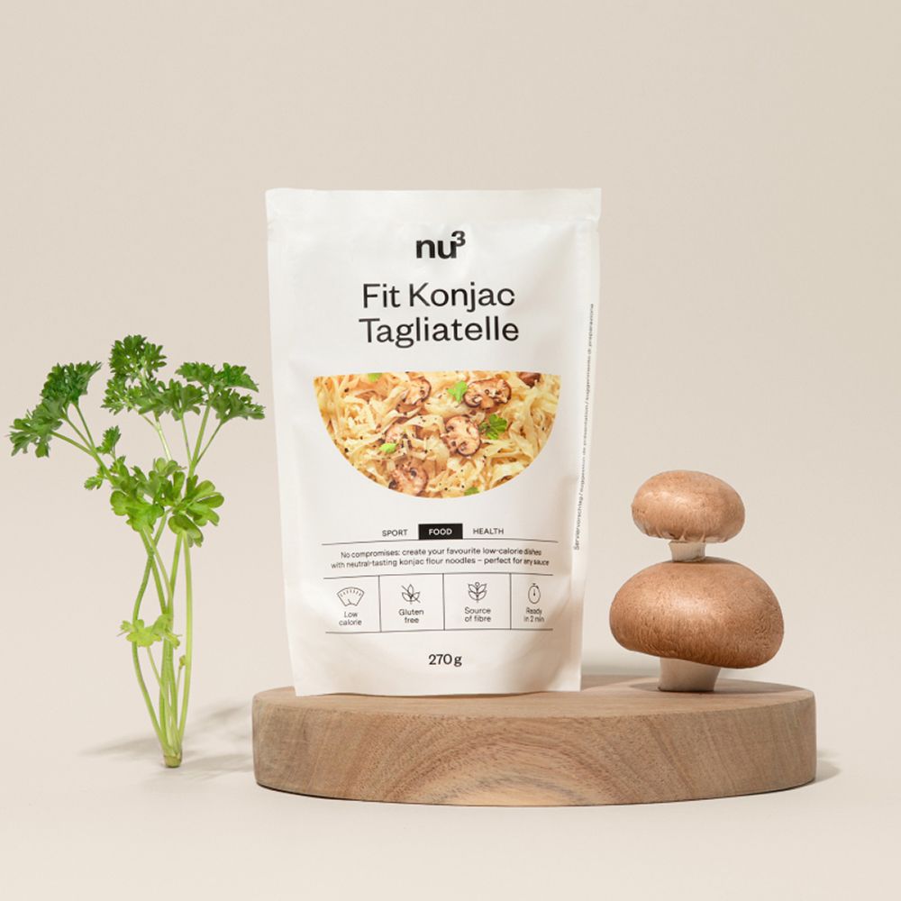 Un paquet de nu3 Fit Konjak Tagliatelle sur une planche en bois avec champignons et persil.