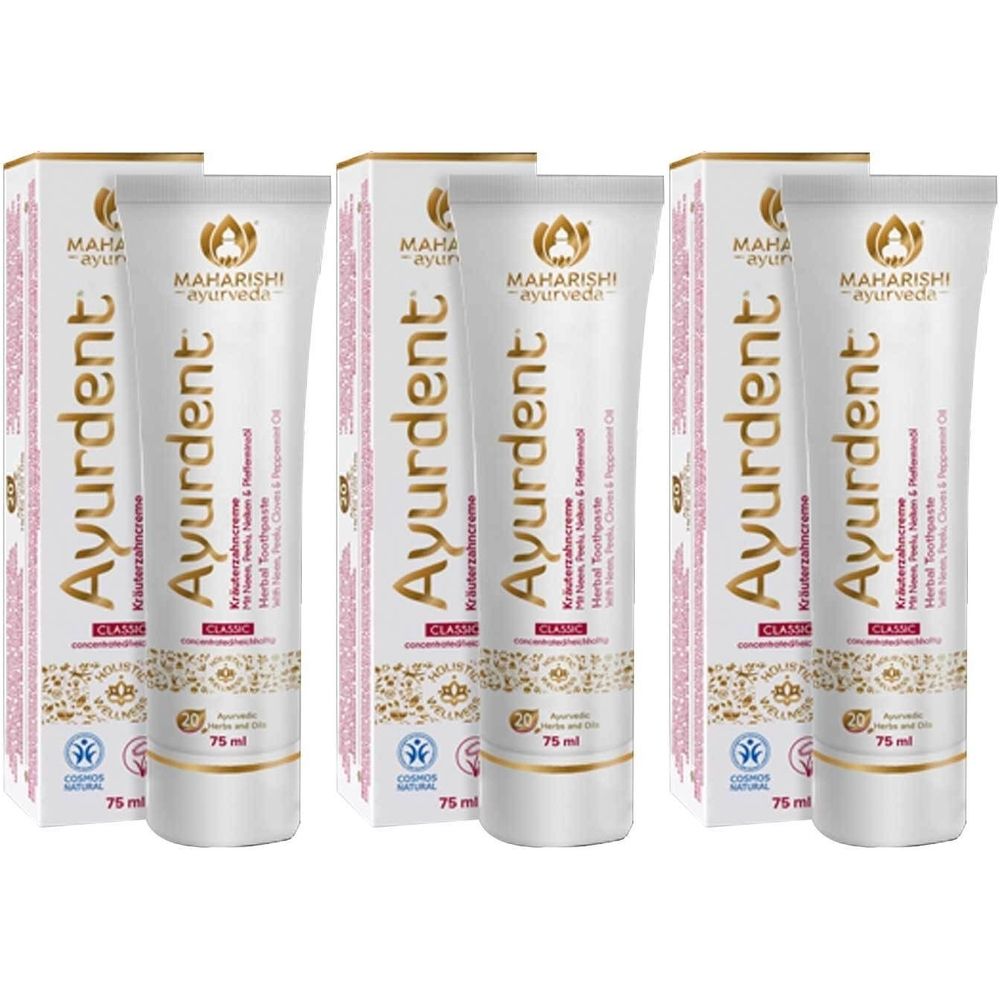 Meerdere tubes en dozen Ayurdent Classic tandpasta. De tubes zijn wit met gouden en rode accenten. Opschriften: merk, productnaam, ingrediënten.