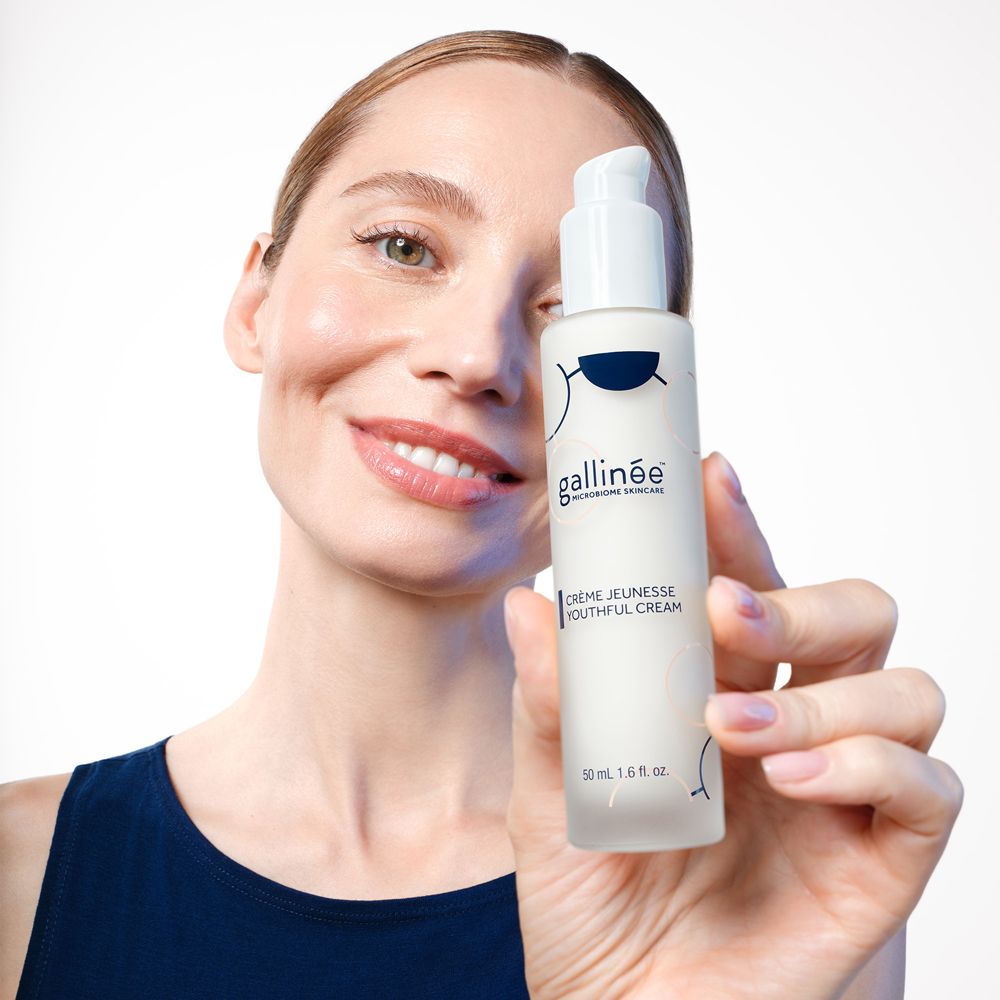 Vrouw houdt crèmefles vast. Witte fles met pomp. Opschrift: gallinée, Crème Jeunesse.