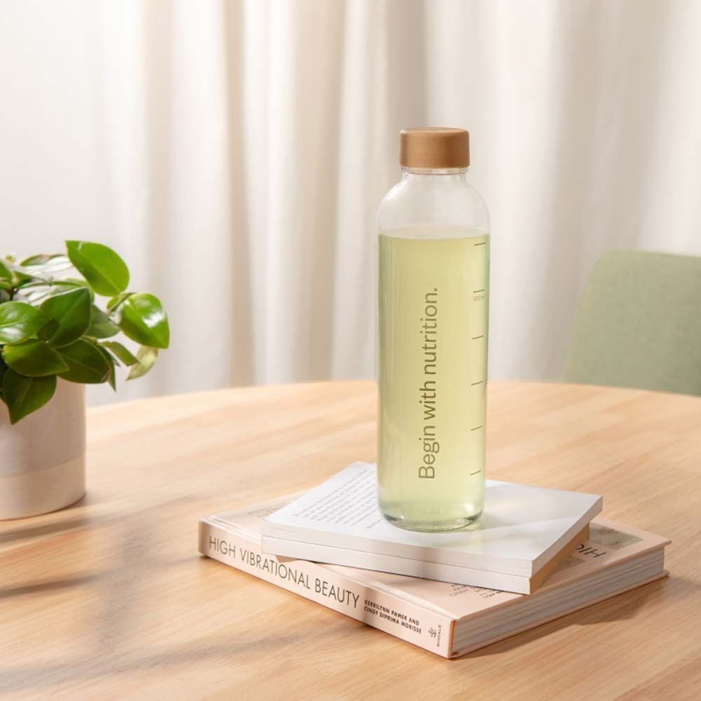 Une bouteille en verre de nu3 Clear Vegan Protein Citron-Citron Vert sur des livres.