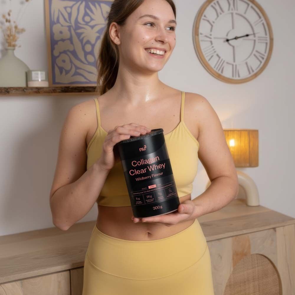 Vrouw houdt een blik nu3 Collagen Clear Whey vast. Zwart blik met roze tekst. Wildberry smaak.