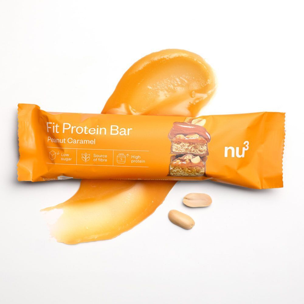 Une barre nu3 Fit Protein, Peanut Caramel, entourée de crème caramel et de cacahuètes.